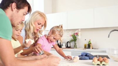 Father and mother kneading a dough with their children