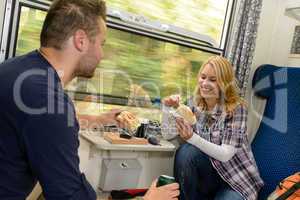 Couple eating sandwiches on train traveling smile