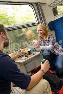 Couple traveling by train eating sandwiches hungry