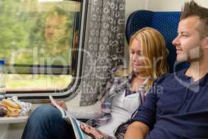 Woman reading magazine man looking train window