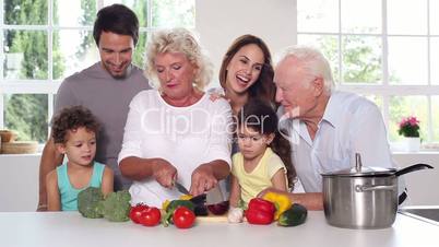 Granny cutting vegetables with the family around