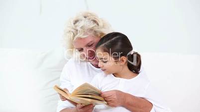 Granny reading book to her granddaughter
