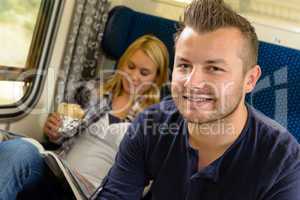 Man smiling sitting on train woman sandwich