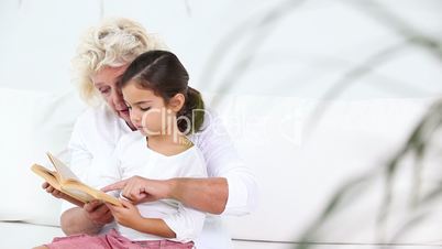Granny reading history to her granddaughter sitting