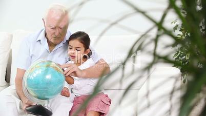 Grandfather and granddaughter looking at globe
