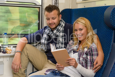 Couple traveling by train woman reading smiling