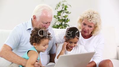 Grandpa and granny using tablet with their grandchildren
