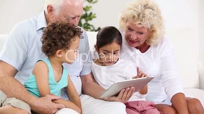 Granny and grandpa using tablet with their grandchildren