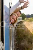 Couple screaming out train window waving happy