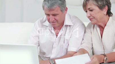 Old man learning to use laptop on the sofa