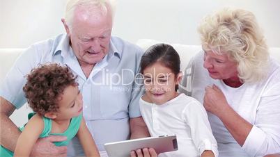 Two grandparents and two children using a tablet