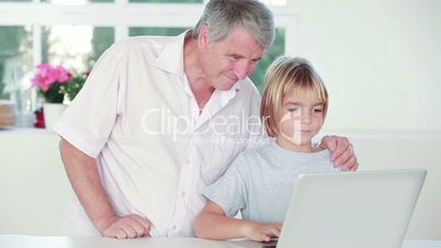 Child using a laptop with his grandpa