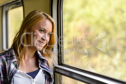 Happy woman looking out train window pensive