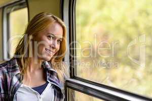 Happy woman looking out train window pensive