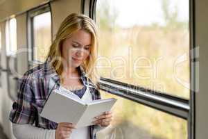 Woman reading a book by train window