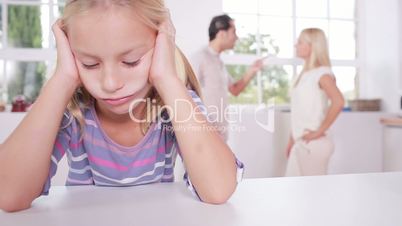 Little girl looking depressed in front of fighting parents