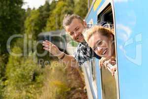 Couple waving with heads out train window