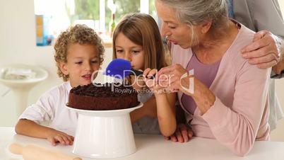 Grandmother icing cake with grandchildren