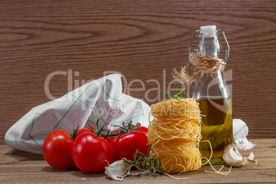 Pasta, tomatoes and herbs on a wooden table
