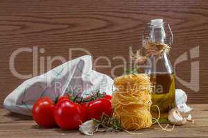 Pasta, tomatoes and herbs on a wooden table