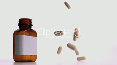 Pills falling beside jar