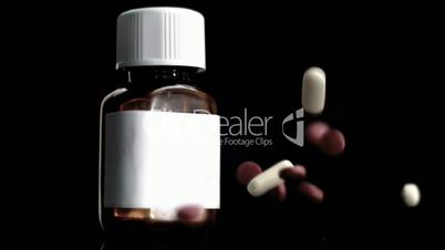 Pills falling beside medicine jar