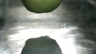 Green apple falling in water