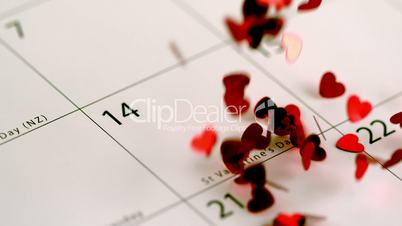 Red heart confetti falling on calendar