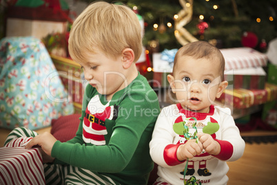 Baby and Young Boy Enjoying Christmas Morning Near The Tree