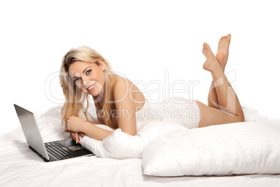 Beautiful blonde using a laptop on a bed