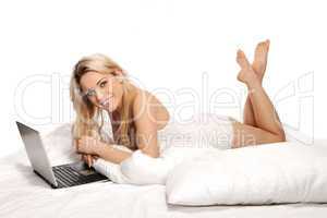 Beautiful blonde using a laptop on a bed