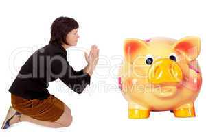 Kneeling woman praying in front of the piggy bank