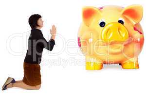 Kneeling woman praying in front of the piggy bank