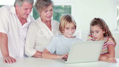 Siblings and grandparents using laptop