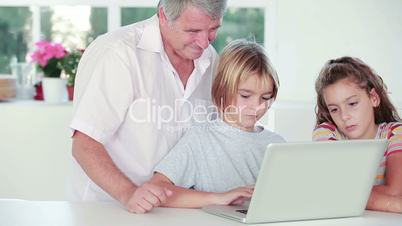 Child learning to use laptop with grandfather