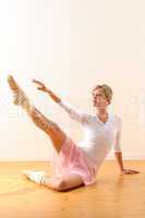 Beautiful ballet dancer lifting arm towards leg