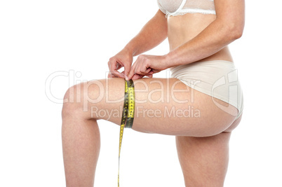 Fit woman in lingeries measuring her thighs