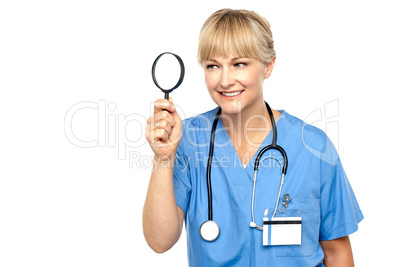 Pretty physician looking through magnifying glass
