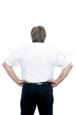 Back pose of a senior man standing with hands on his waist