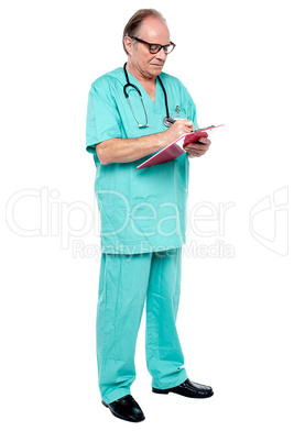Mature medical practitioner writing case history of a patient