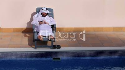 arabian using phone at pool
