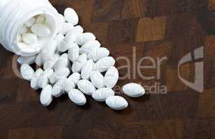 Glass of pills on wood background