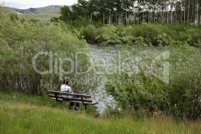 Woman relaxes on bench beside lake