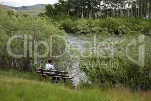 Woman relaxes on bench beside lake