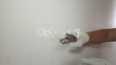 Man in glove showing how to remove old wallpaper