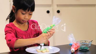 Cute Asian Girl Decorates Christmas Cookie