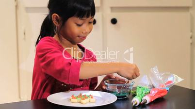 Asian Girl Adds Sprinkles To Christmas Cookie