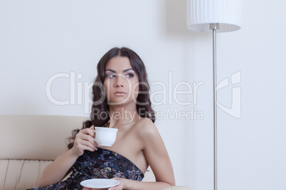 Brunette woman drinking coffee in living room