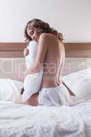 Woman with pillow sitting on bed