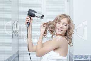 Happy woman with hairdryer in bathroom